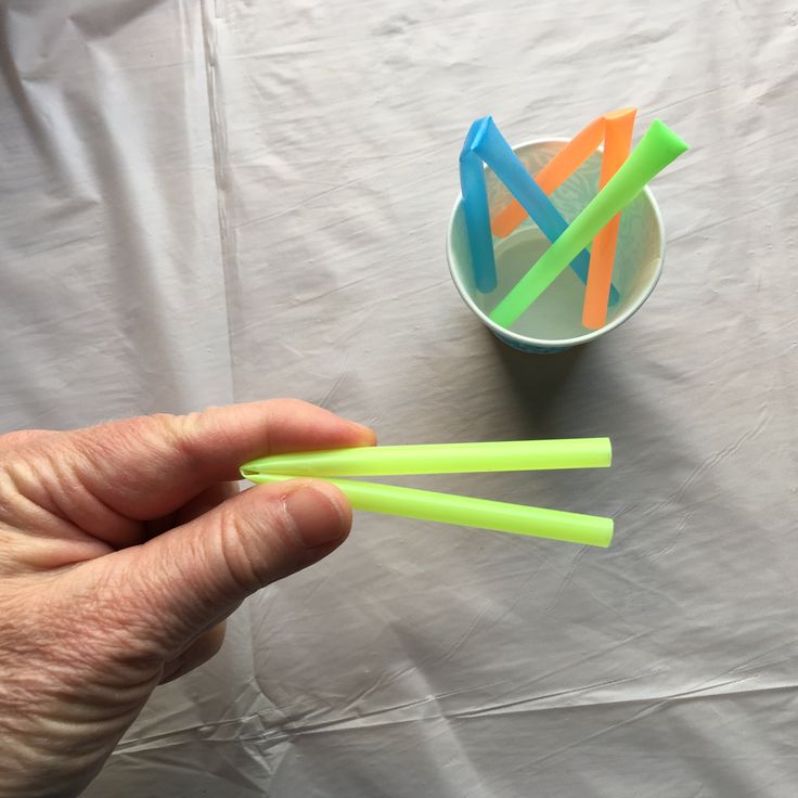 a person holding three plastic straws in their hand