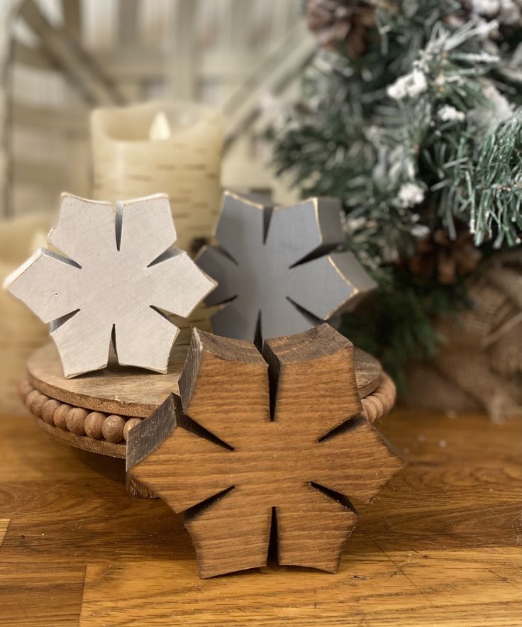 two wooden snowflakes sitting on top of a table next to a christmas tree