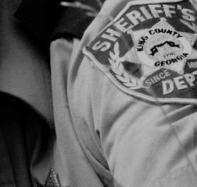 a black and white photo of a person wearing a sheriff's badge on his shirt