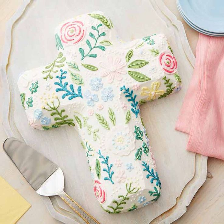 a cross shaped cake sitting on top of a plate next to a knife and fork