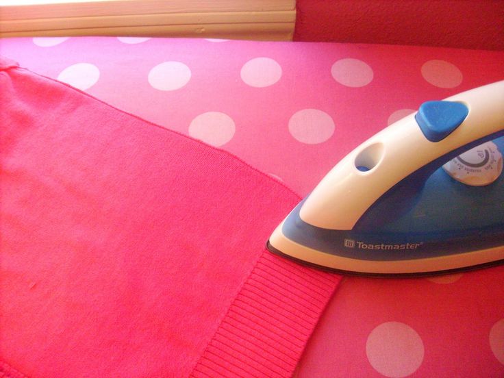 an iron is sitting on top of a pink bed with white polka dot print sheets