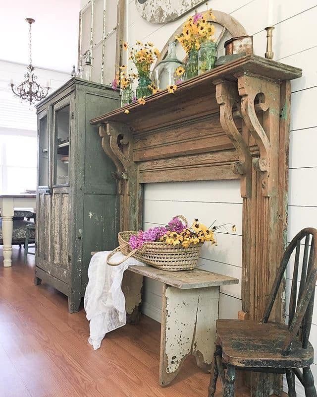 an old fireplace with flowers on top and a basket full of daisies sitting next to it