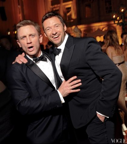 two men in tuxedos standing next to each other at a formal dinner table