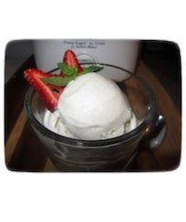 a glass bowl filled with ice cream and strawberries on top of a wooden table