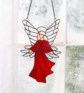 a stained glass angel hanging on a window sill in front of snow covered windows