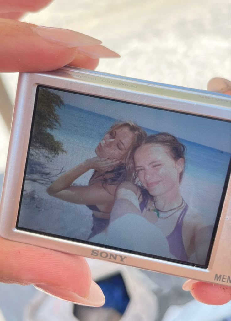 a person holding up a polaroid with two women on it