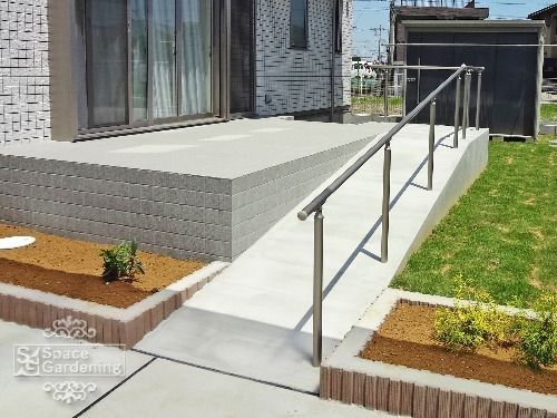 a house with a metal hand rail in front of it and grass on the ground