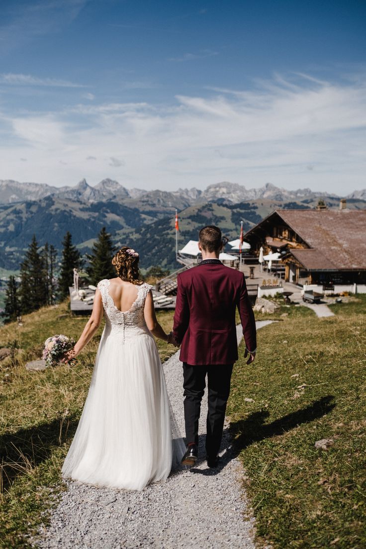 a bride and groom walking down a path in the mountains with their back to the camera