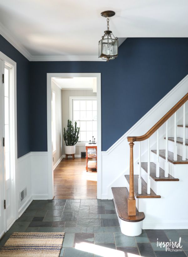 an entryway with blue walls and white trim on the stairs is flanked by a wooden banister