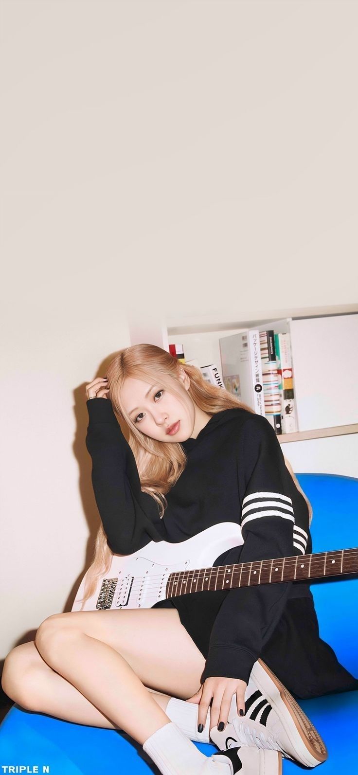 a young woman sitting on top of a blue couch holding a black and white guitar