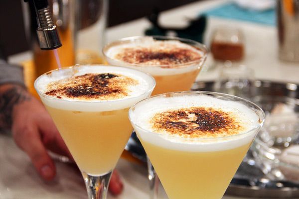 three glasses filled with drinks sitting on top of a table