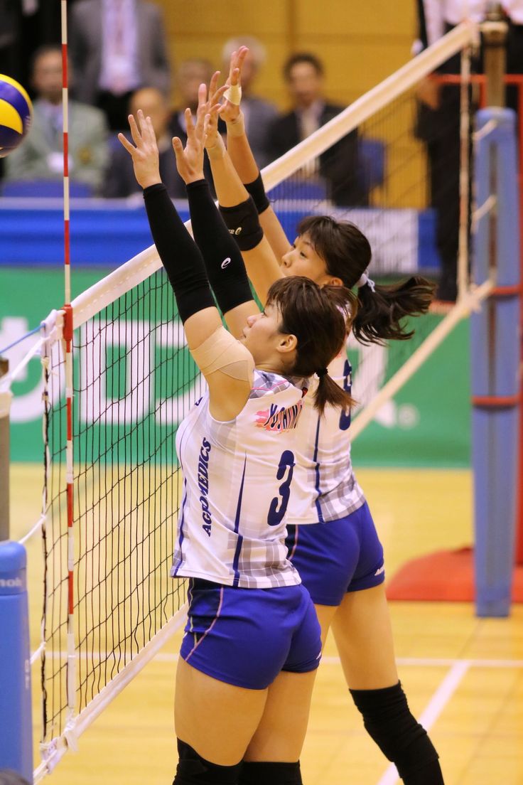 two female volleyball players reaching for the ball