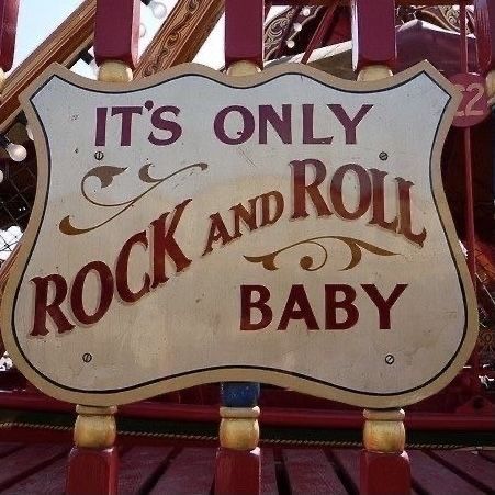 a sign that says it's only rock and roll baby on the back of a carnival ride