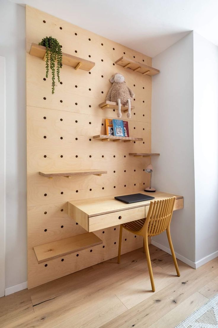 a wooden desk sitting in front of a wall mounted shelf with books on top of it