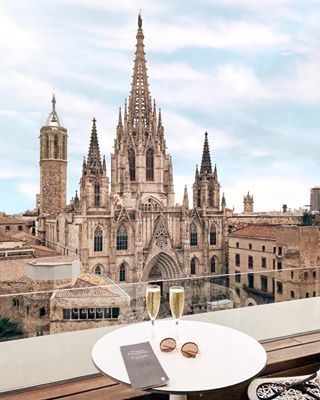 two glasses of wine are sitting on a table in front of a view of the city