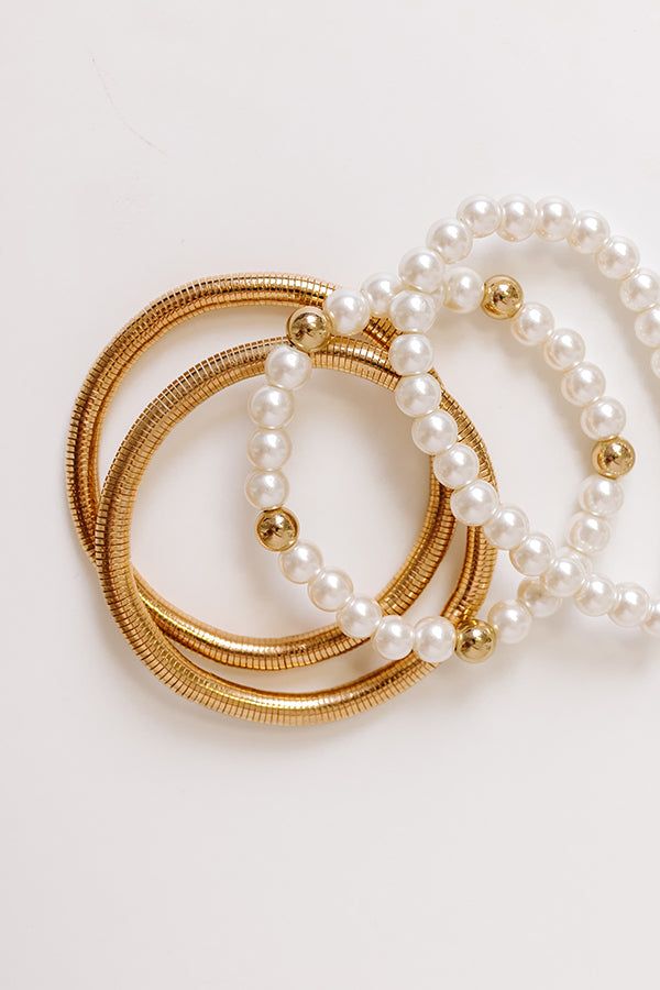 - Get ready for the gala with this gorgeous stackable bracelet set! - A set of 4 stretchy bracelets - Gold colored metal material - Two stretchy spring bracelets - Two faux pearl and gold beaded bracelets Spring Pearl Gold Jewelry, Spring Gold Pearl Jewelry, Spring Festival Gold Jewelry With Round Beads, Spring Gold Jewelry With Round Beads, Gold Round Beads Bracelets For Spring, Gold Bracelets With Round Beads For Spring, Gold Round Beads Bracelet For Spring, Spring Gold Bracelets With Round Beads, Trendy Gold Pearl Beaded Bracelets