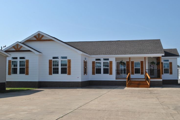 a small white house with brown shutters on the front and side windows, sitting in an empty lot