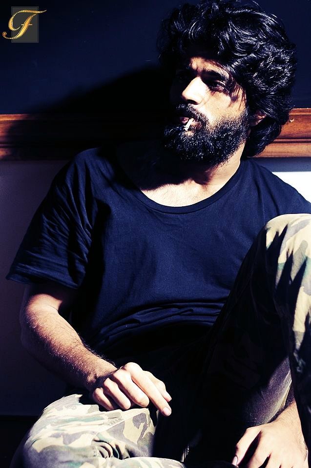 a man with long hair and beard sitting on the floor in front of a wall