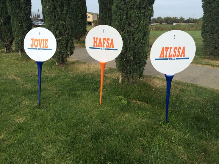 three white and orange signs sitting in the grass next to each other on top of trees