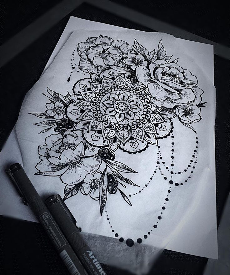 a black and white drawing of flowers on a piece of paper next to a pen