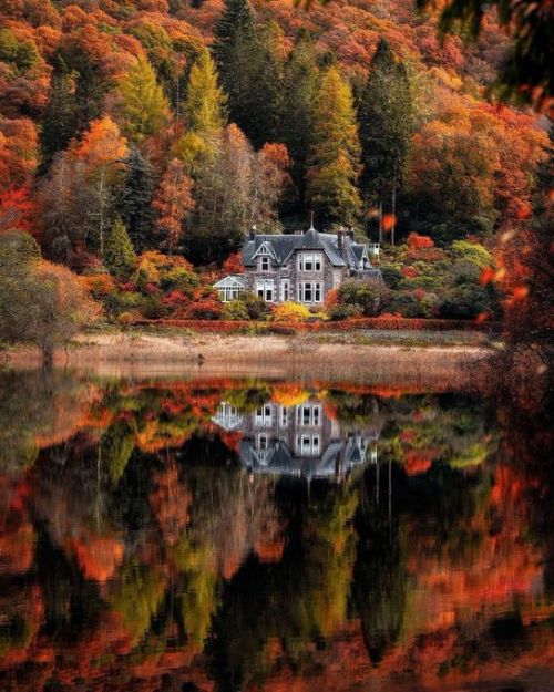 a large house sitting on top of a lake surrounded by trees