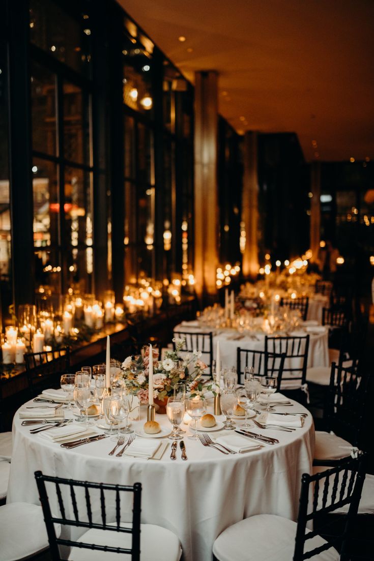 the tables are set with candles and place settings for an elegant dinner or reception at night