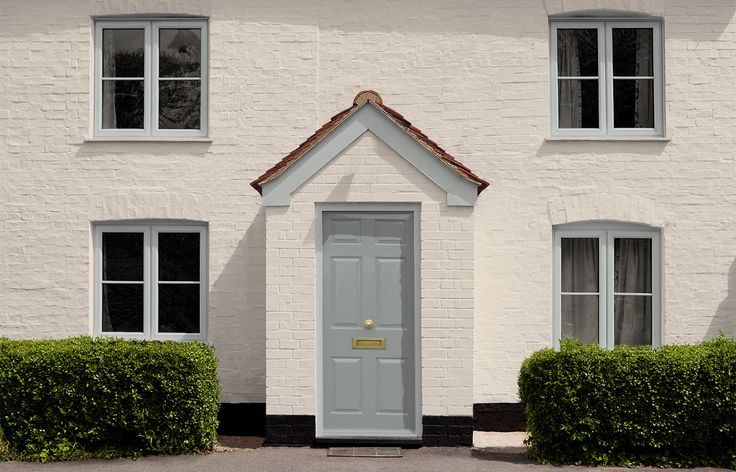 a white brick house with black shutters and a yellow sign on the front door