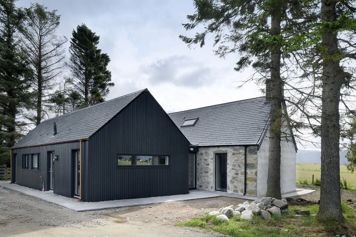 a black house surrounded by trees and grass