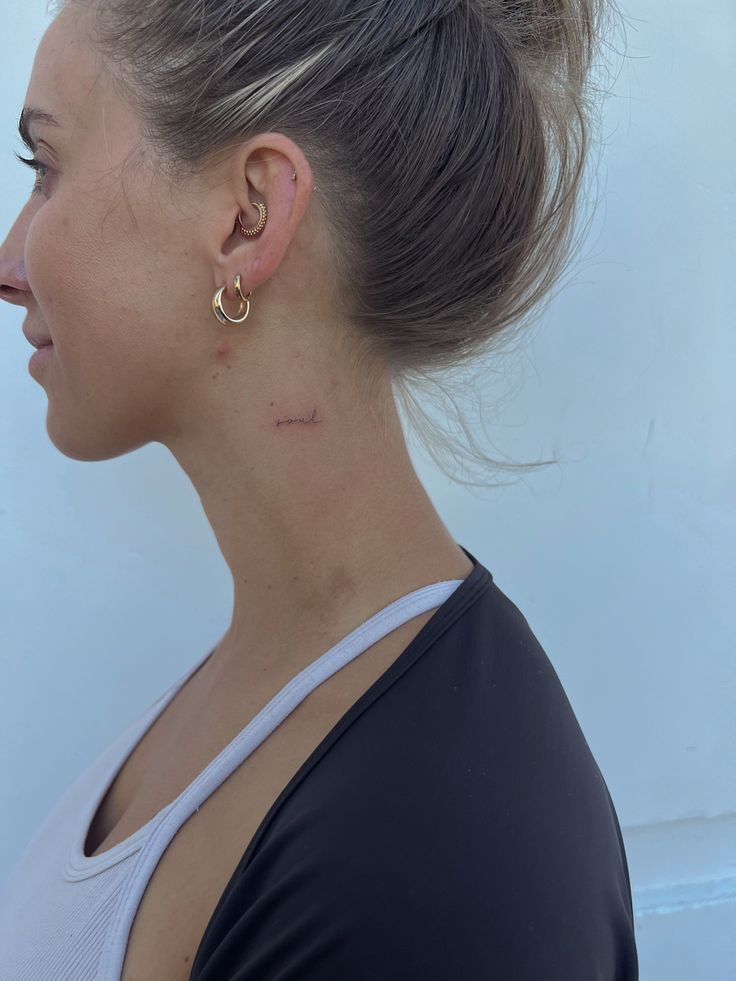 a close up of a person with ear piercings on their ears and behind her is a white wall