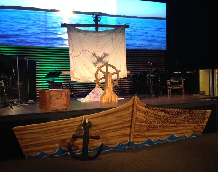 a large wooden boat sitting on top of a stage next to a cross and an anchor