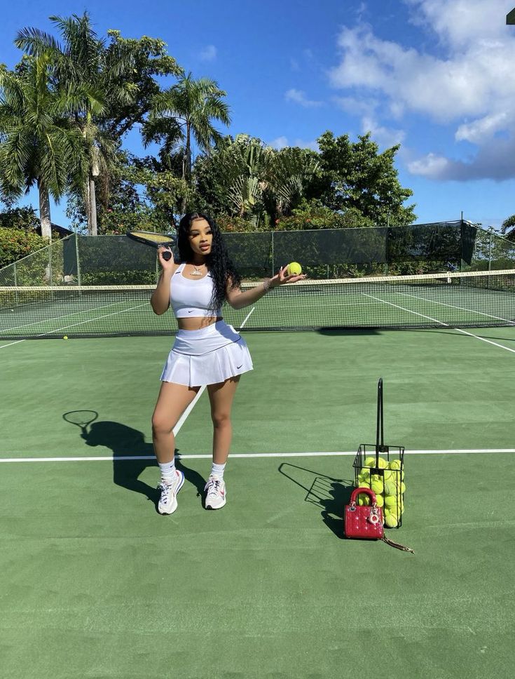 a woman holding a tennis racquet standing on top of a tennis court next to a ball and racket