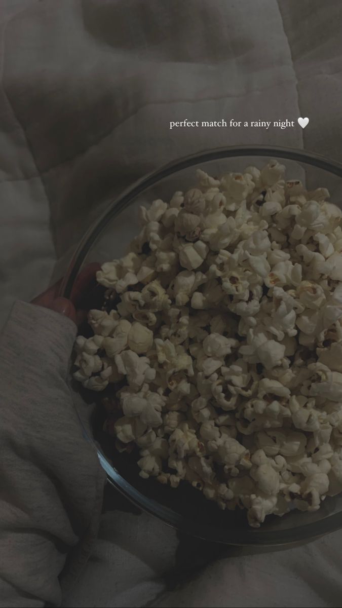 a bowl filled with popcorn sitting on top of a bed