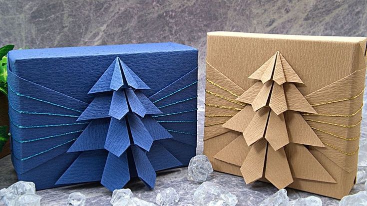 two origami christmas trees are sitting next to each other