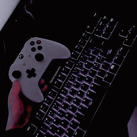 a person is holding a controller over a computer keyboard with the key board on it