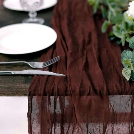 the table is set with plates and silverware on it, along with greenery