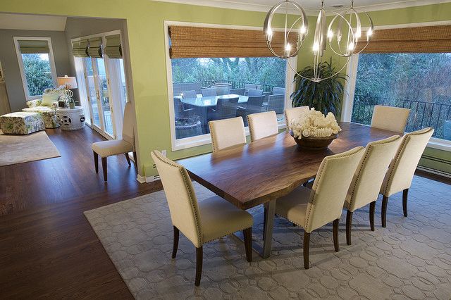 a dining room table with chairs and a vase on it in front of a large window