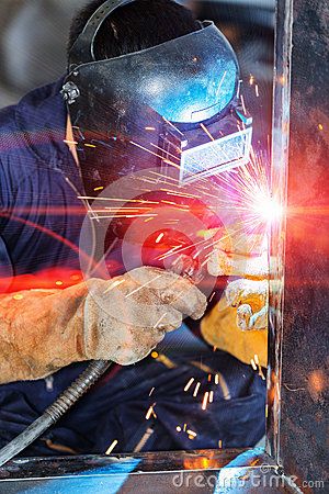 welder working on an industrial project with sparks coming out of his face and hands