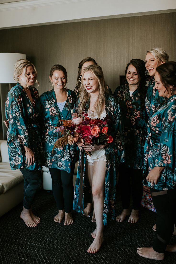 a group of women standing next to each other wearing matching robes and holding bouquets