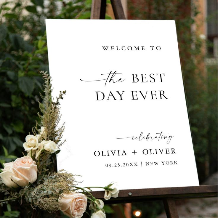 a welcome sign for the best day ever with flowers and greenery in front of it