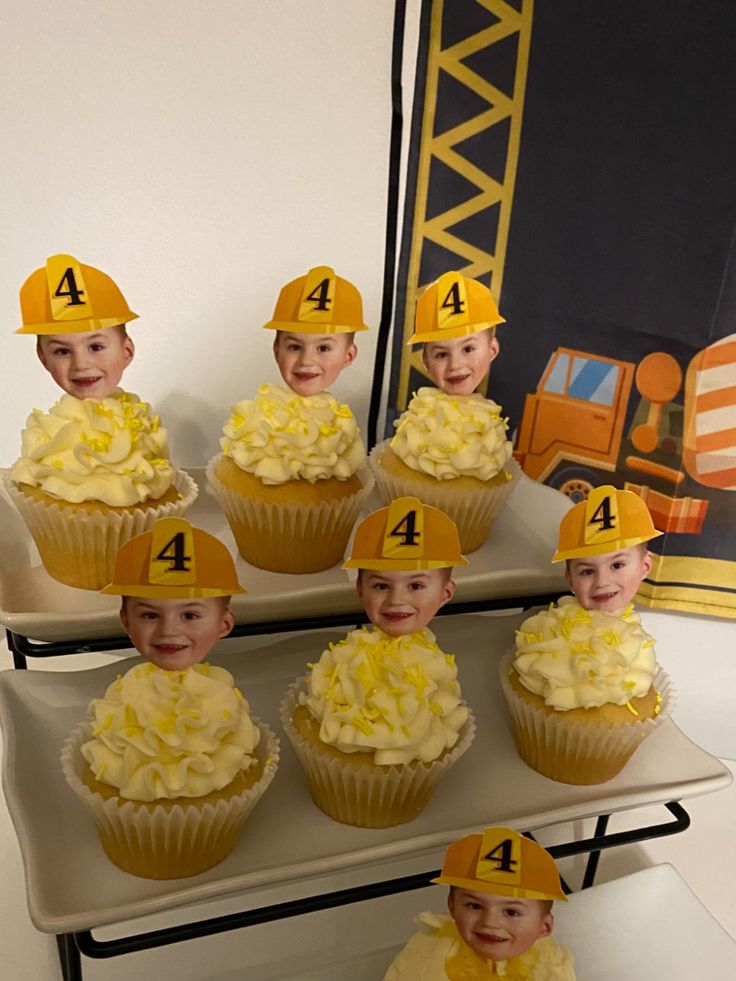 cupcakes with yellow frosting and fireman hats on them are sitting in front of a sign