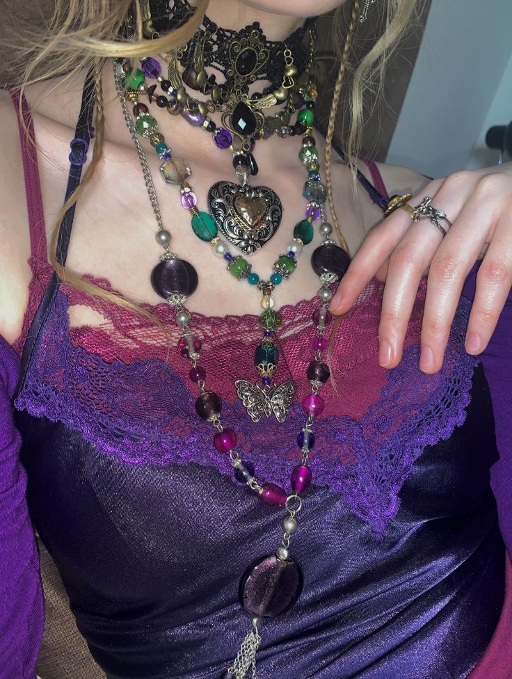 a woman wearing a purple top with lots of necklaces on her neck and chest