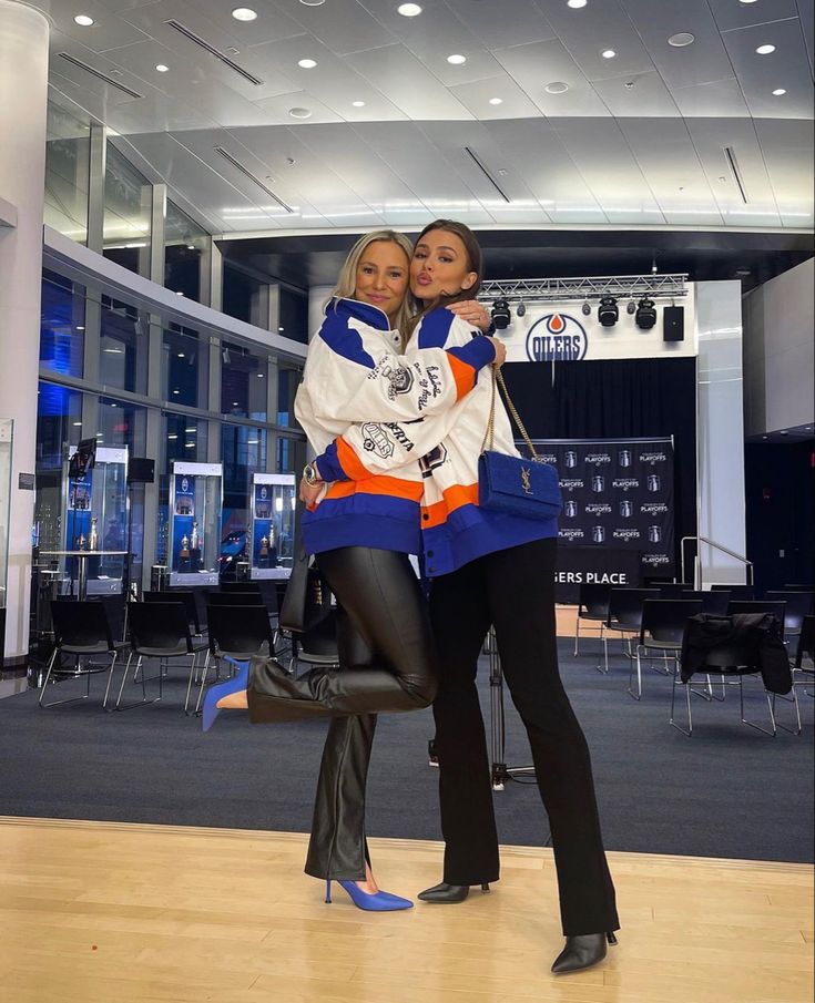 two women standing next to each other on a wooden floor