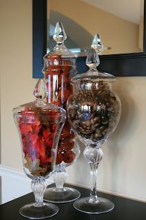 two glass vases filled with candy on top of a black table next to a mirror