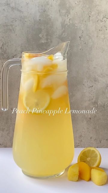 a pitcher filled with lemonade next to sliced lemons