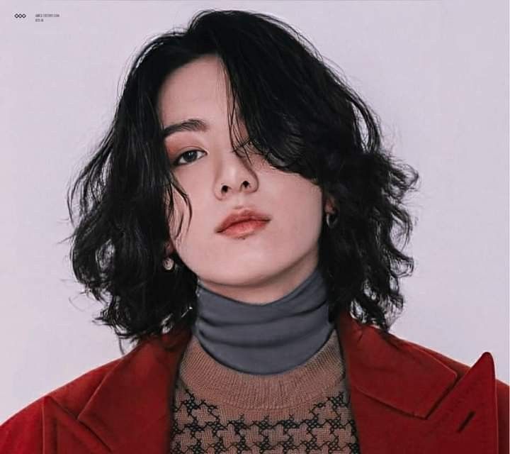 a woman with black hair wearing a red jacket and turtle neck sweater is looking at the camera