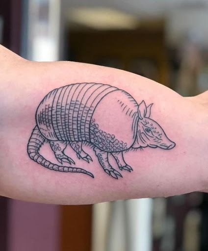 a arm with a black and white rat tattoo on it