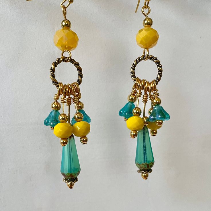 A sunny pair of earrings!  Golden rings hold faceted turquoise glass drops, yellow faceted glass beads and turquoise-colored flowers set off with small gold-plated beads. Larger faceted yellow glass beads hold each ring, and are topped with a small plated bead.  Total earring length is 3 inches. Yellow And Teal Clothing Accessories, Bohemian Gold Faceted Earrings, Yellow Beaded Czech Glass Earrings, Yellow Beaded Earrings With Czech Glass, Yellow Beaded Earrings In Czech Glass, Nickel-free Yellow Dangle Beaded Earrings, Nickel Free Yellow Dangle Beaded Earrings, Bohemian Gold Earrings With Faceted Beads, Yellow Teardrop Earrings With Dangling Beads