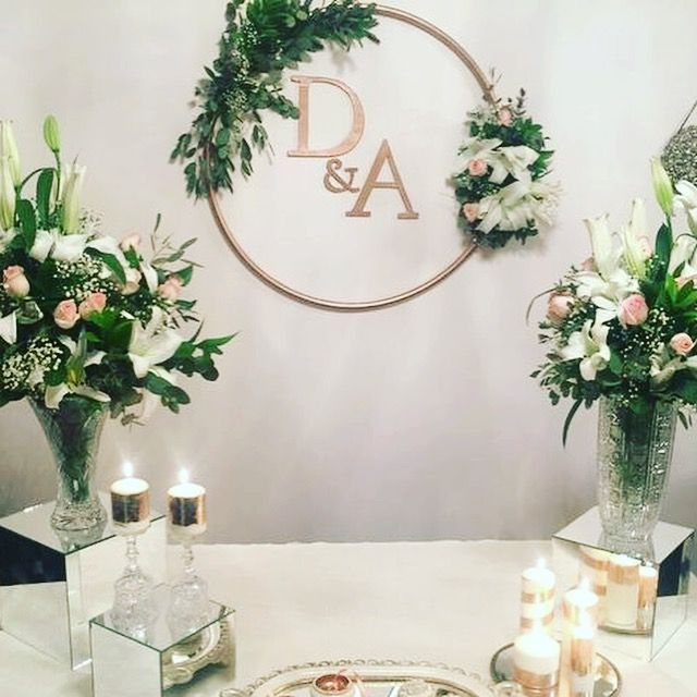 two vases with flowers and candles on a table in front of a sign that says d & a