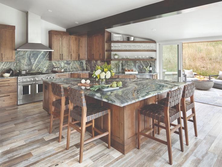 a kitchen with marble counter tops and wooden cabinets, along with an island in the middle