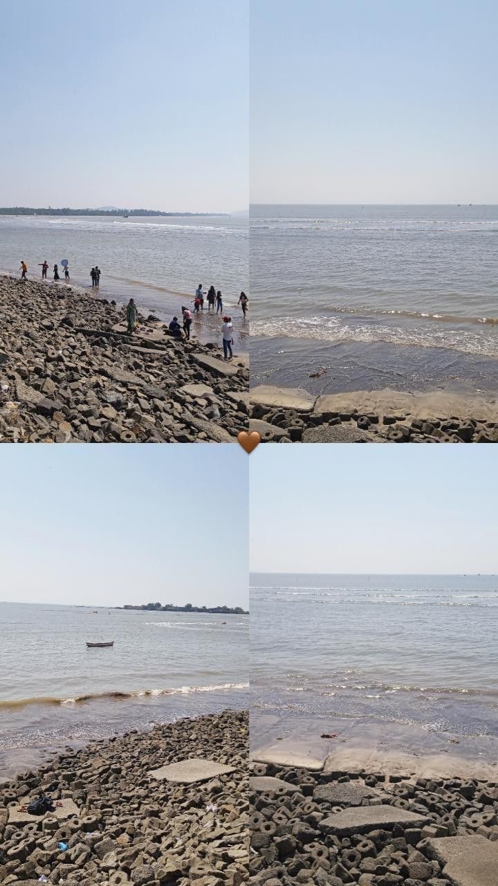 people are walking on the beach and in the water at low tide, with rocks scattered around them